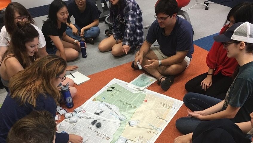 Students huddle around a map on the floor during a 2017 study abroad class in Japan.